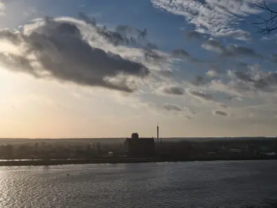 Panorama Płocka nad Wisłą o zmierzchu, z szeroką rzeką na pierwszym planie i sylwetką miasta na horyzoncie