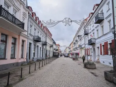 Brukowana ulica w centrum Płocka z rzędami odnowionych kamienic z balkonami i dekoracjami świetlnymi nad deptakiem