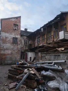 Zniszczone podwórze starej kamienicy w Płocku z walącym się balkonem i stertą gruzu
