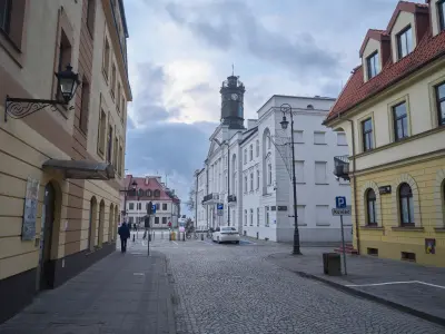 Brukowana ulica starówki w Płocku prowadząca do białego ratusza z wieżą zegarową i otaczających go kamienic