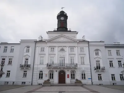 Frontowa fasada białego Ratusza Miejskiego w Płocku z wieżą zegarową i rzeźbami lwów przy wejściu