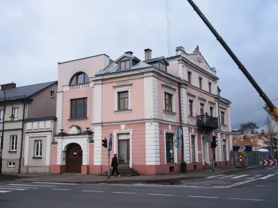 Historyczna różowo-biała kamienica „Brama 1922” z balkonem, przy skrzyżowaniu ulic we Włocławku