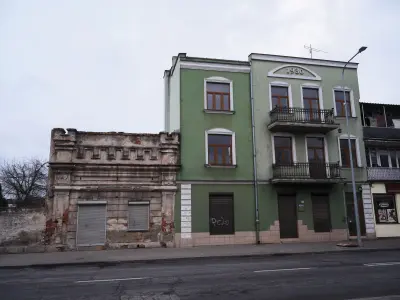 Zielona kamienica z 1930 roku w Płocku stojąca obok zrujnowanego ceglanego muru przy ulicy