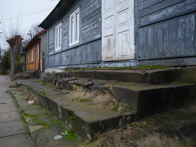 Zniszczone kamienne schody porośnięte mchem przed starym drewnianym domem przy ulicy w Czerwińsku nad Wisłą