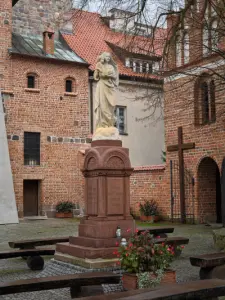 Kamienna figura Matki Bożej z Dzieciątkiem na cokole na dziedzińcu ceglanego klasztoru w Czerwińsku