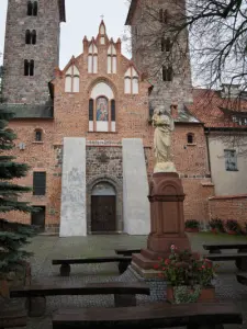 Ceglana fasada bazyliki Zwiastowania NMP w Czerwińsku nad Wisłą z wieżami i figurą Maryi na dziedzińcu