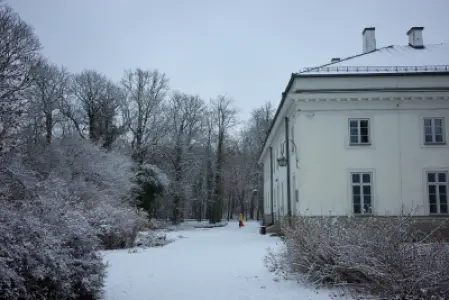 Zimowy Pałac Myślewicki w Łazienkach Królewskich, ośnieżony park i alejka wśród drzew