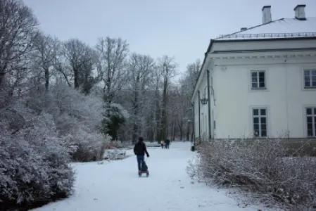 Zimowy spacer przy ośnieżonej alei obok jasnej fasady Pałacu Ujazdowskiego w Warszawie