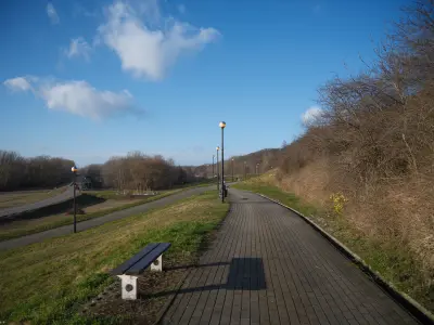 Pusta ścieżka spacerowa na wale przeciwpowodziowym nad Wisłą w Płocku z ławką i latarniami