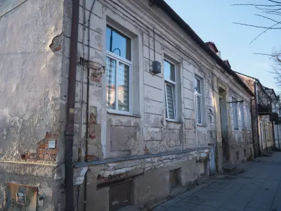 Zniszczona parterowa kamienica przy ulicy Kościuszki 14 w Płocku, z łuszczącym się tynkiem i oknami od strony chodnika