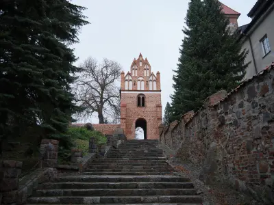 Kamienne schody prowadzące do gotyckiej ceglanej bramy klasztornej w Czerwińsku nad Wisłą, otoczonej murami